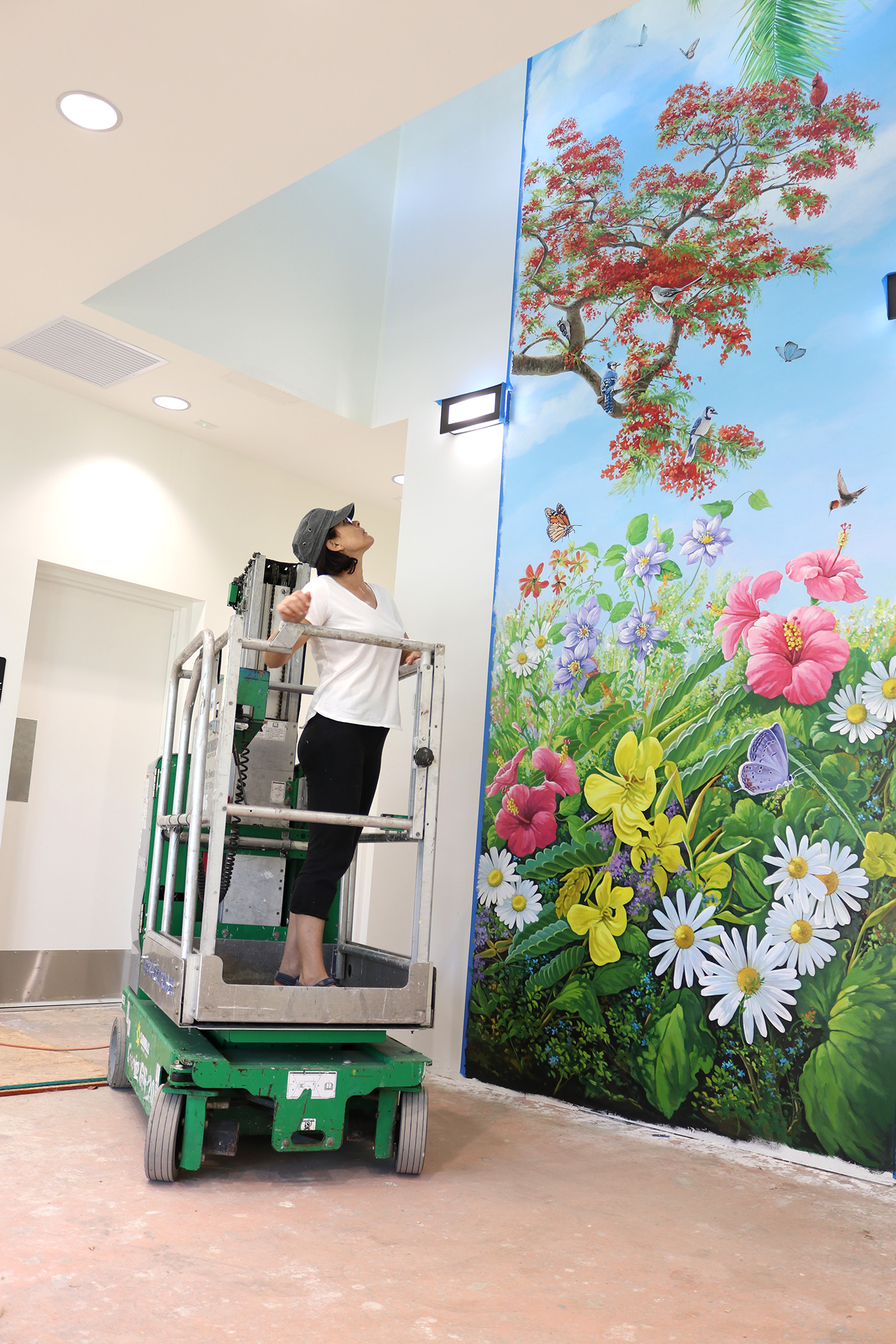 Mural artist on scaffold working on mural